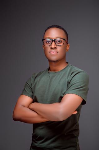 Young man with glasses, standing arms crossed, facing the camera