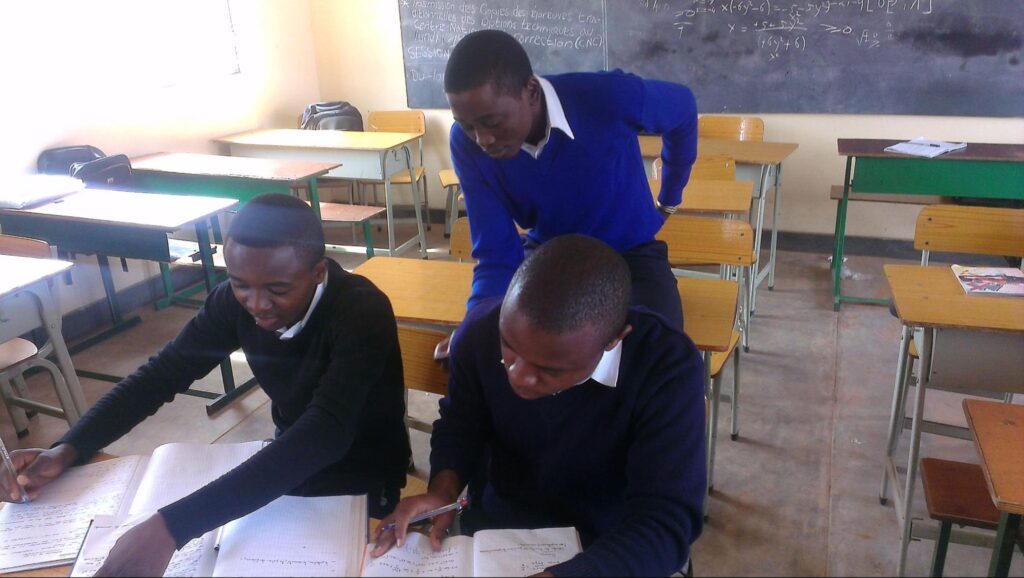 three students in a classroom in congo