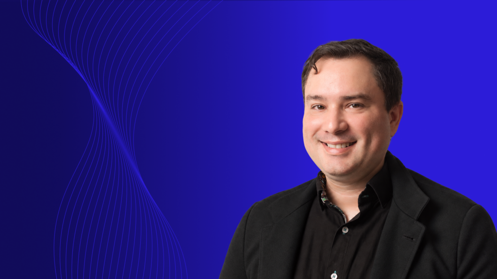 Portrait of a man in front of blue background, smiling and looking at the camera